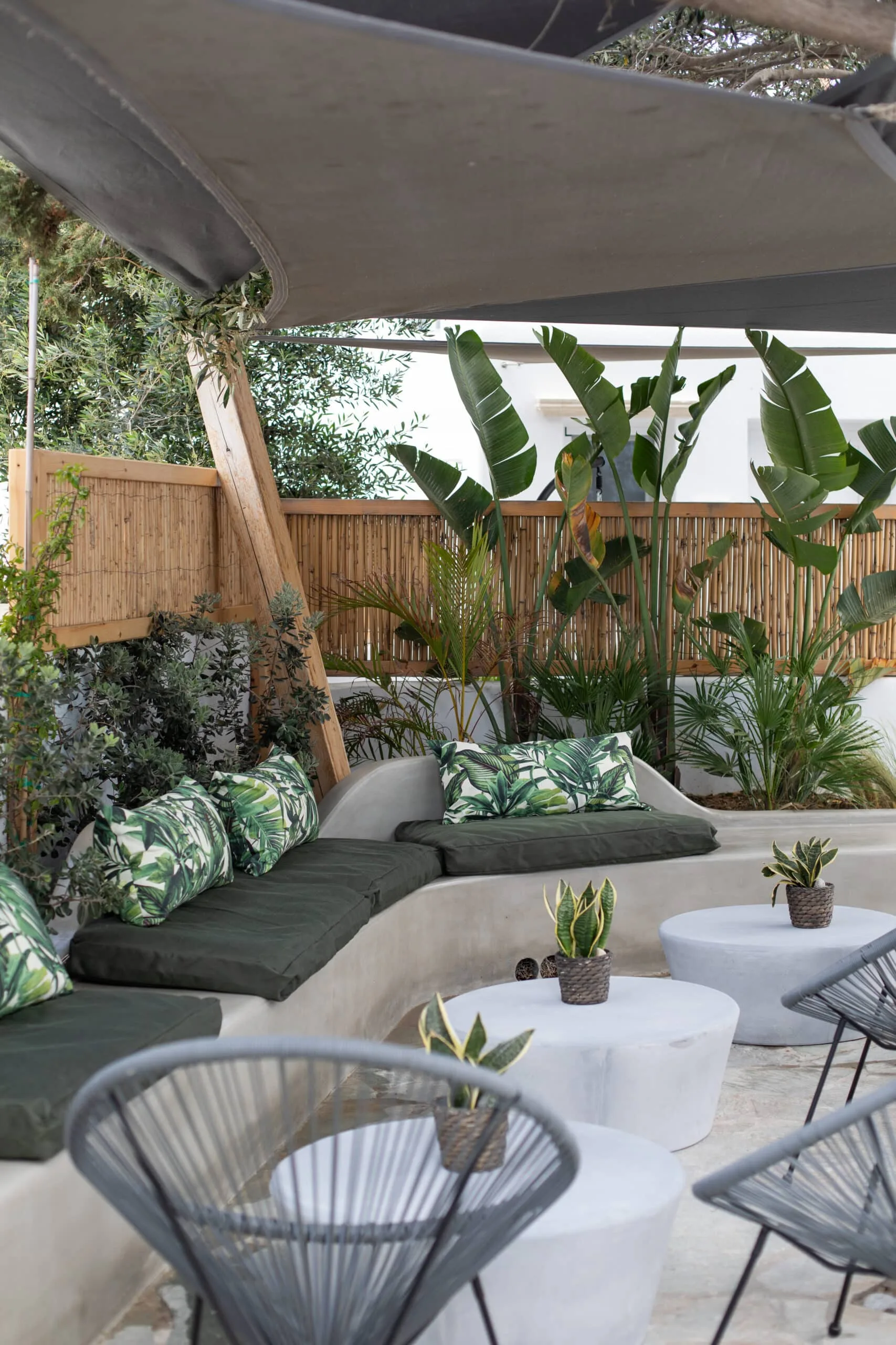 Lounge corner with leaf-print cushions under the shade sail